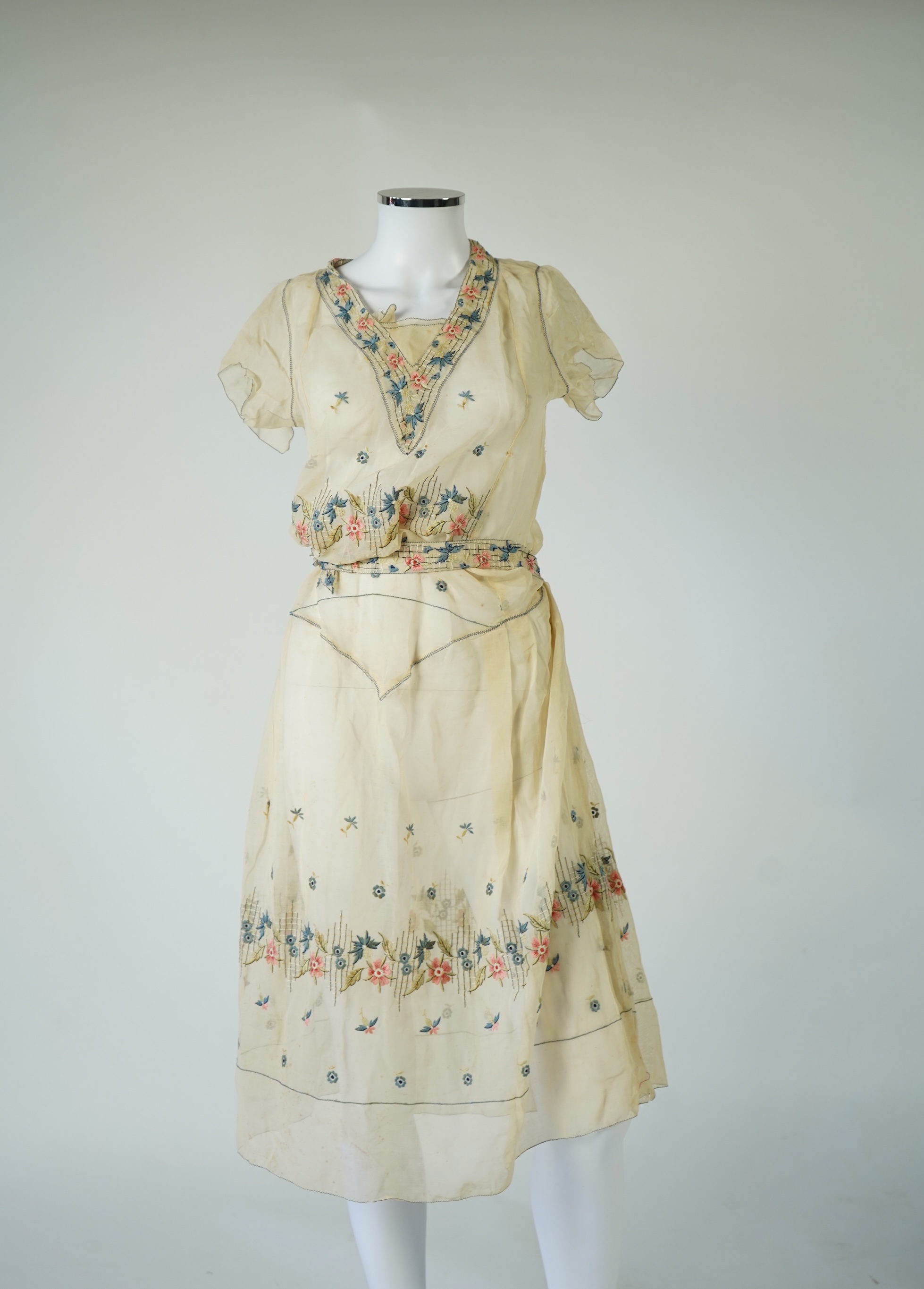 An unusual 1920's fine cream lawn summer dress with hand embroidered blue, pink, flowers, tie and picot edging., 116cm long. Condition - some small rust stains and one small tear at the back right shoulder.